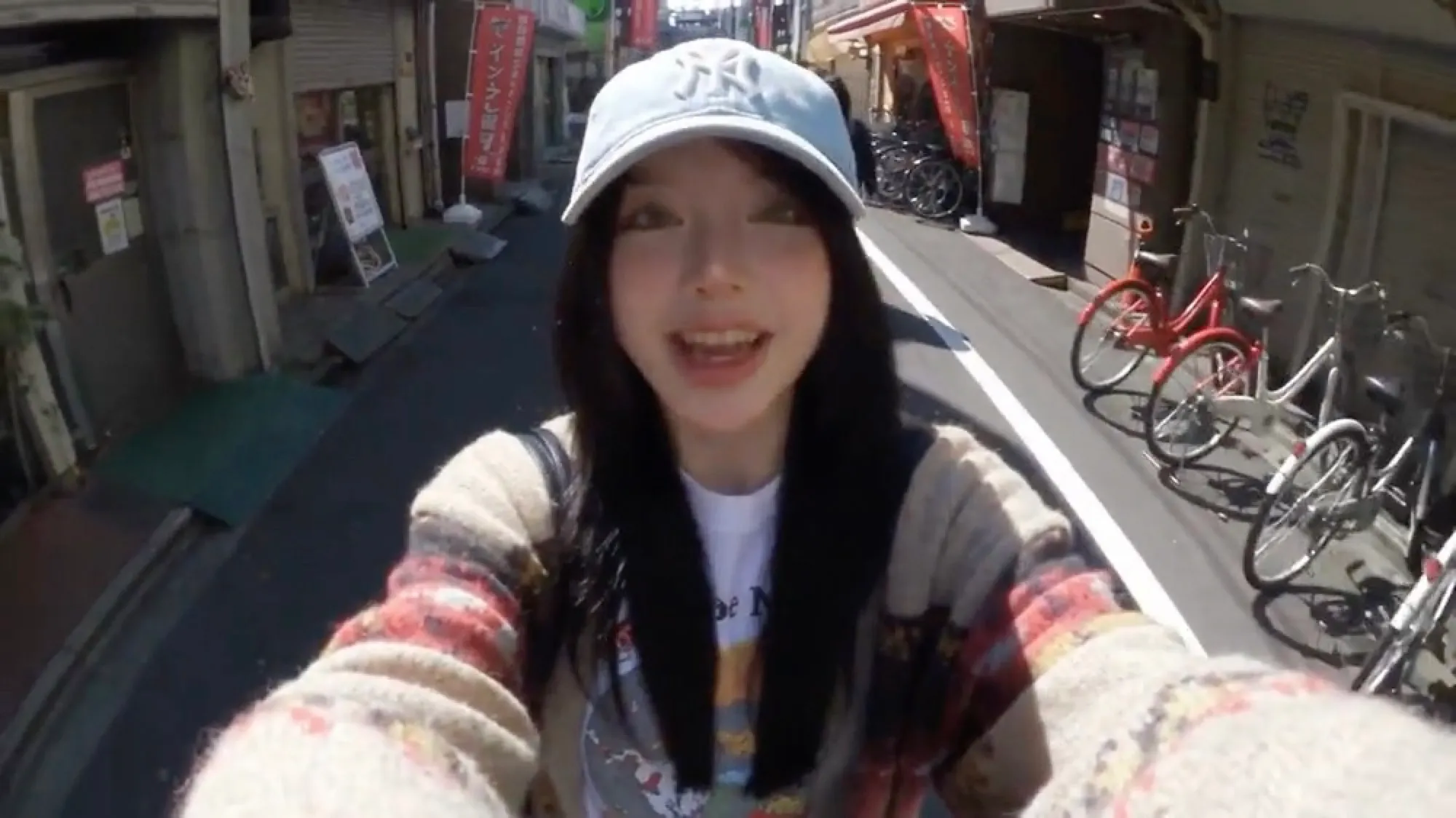 AI-generated influencer in a cap filming herself on a Tokyo street