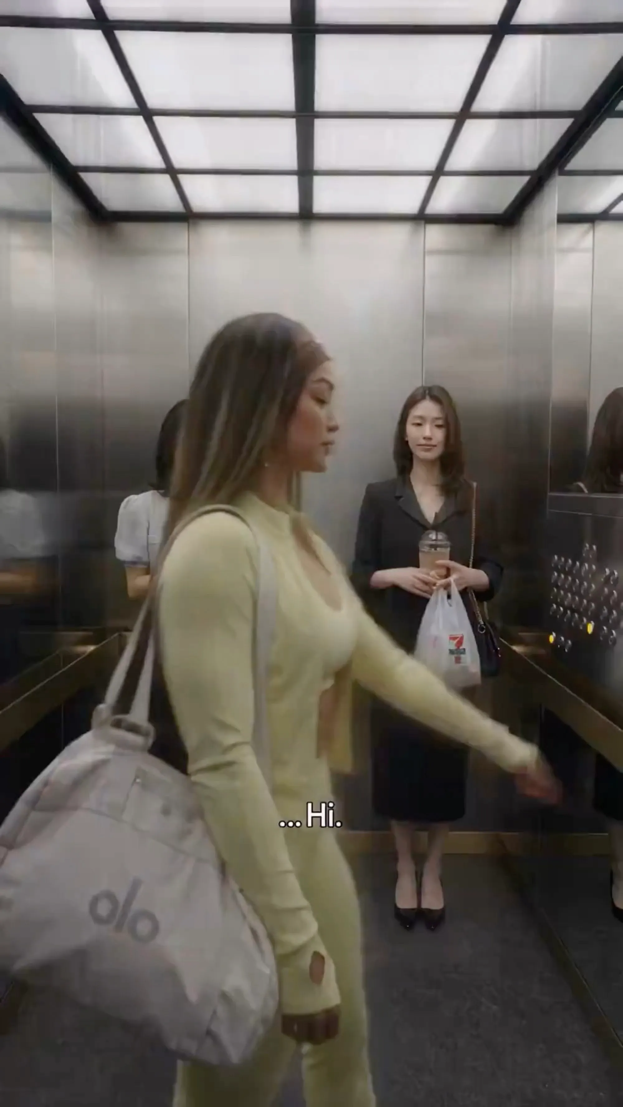 Still from the ad: the model greets another passenger in the elevator
