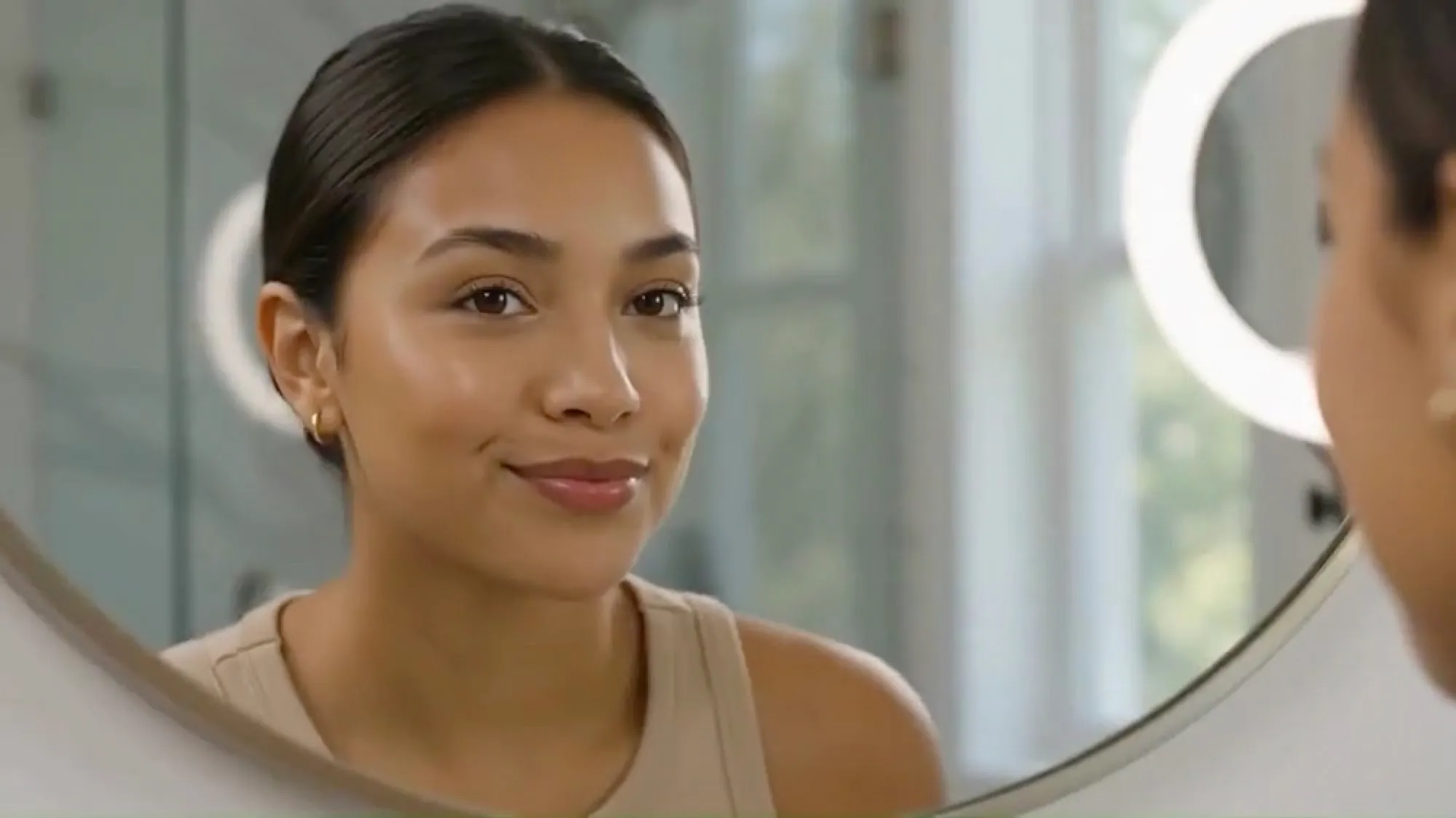 Woman smiling at a mirror, still from the lip balm ad